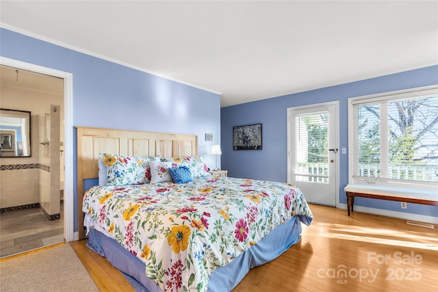 bedroom featuring access to outside, crown molding, ensuite bath, and wood finished floors