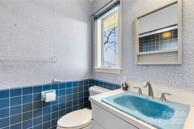 bathroom featuring toilet, vanity, and tile walls