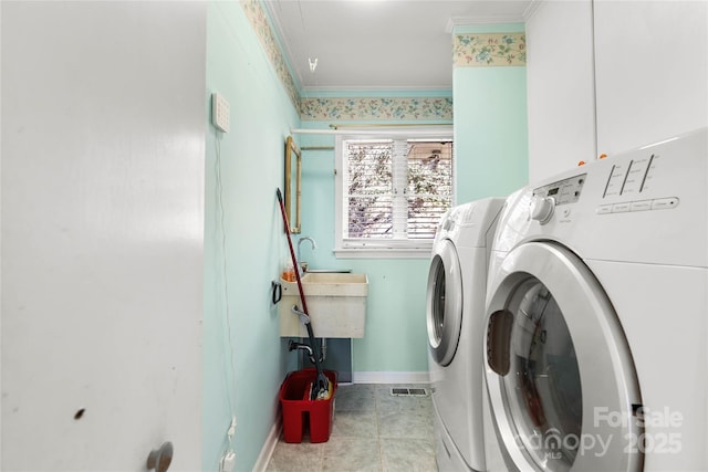 clothes washing area featuring cabinet space, ornamental molding, washing machine and dryer, a sink, and light tile patterned flooring