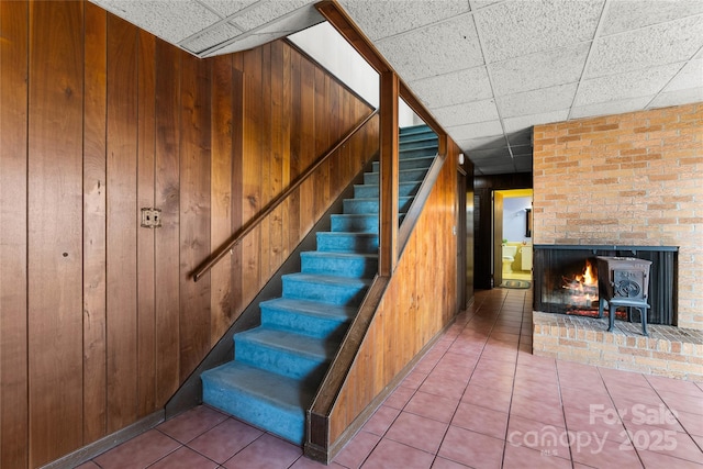 stairway featuring wood walls, a drop ceiling, and tile patterned floors