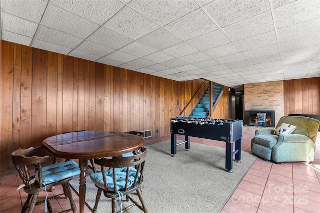 rec room featuring a large fireplace, visible vents, wood walls, and tile patterned floors