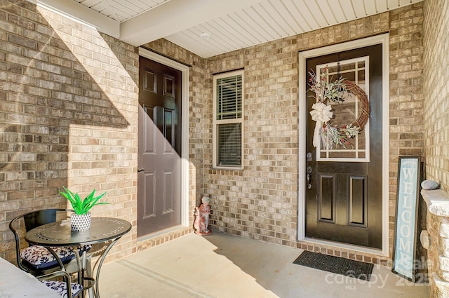 view of exterior entry featuring brick siding and a porch