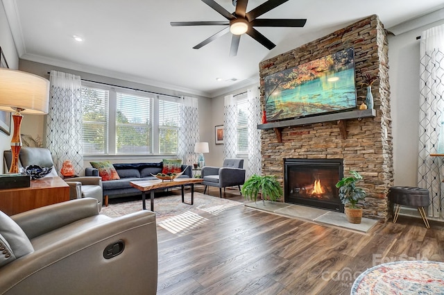 living room with ceiling fan, wood finished floors, a fireplace, and ornamental molding