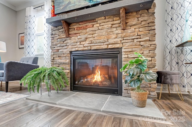 room details with a fireplace, crown molding, baseboards, and wood finished floors