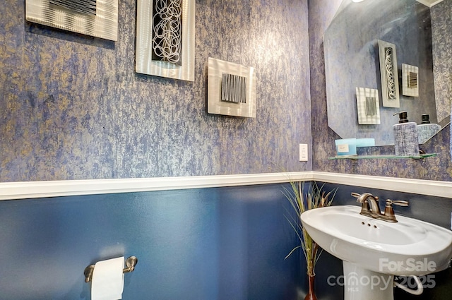 bathroom featuring a sink and wallpapered walls