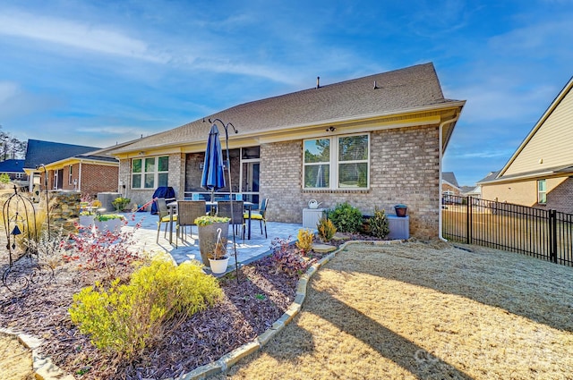 rear view of property with brick siding, a patio area, and fence