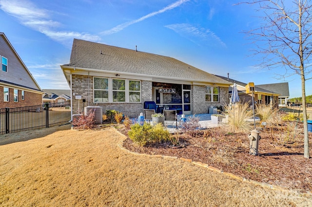 back of house with brick siding, fence, roof with shingles, central AC, and a patio area