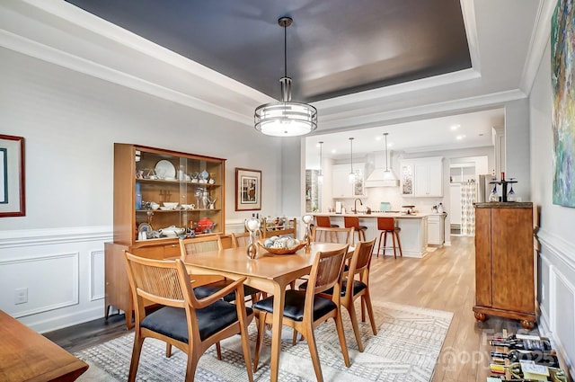 9428 Liberty Hill Dr, Mint Hill, NC 28227 - dining area with crown molding, a raised ceiling, light wood-style floors, wainscoting, and a decorative wall