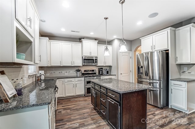 kitchen with sink, a center island, pendant lighting, stainless steel appliances, and white cabinets