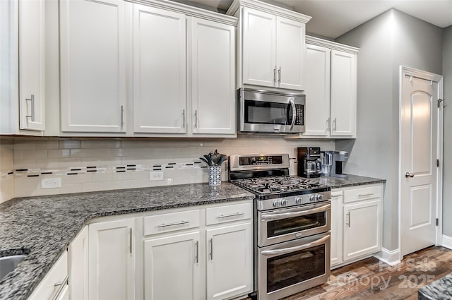 kitchen with white cabinetry, dark wood-type flooring, tasteful backsplash, and appliances with stainless steel finishes