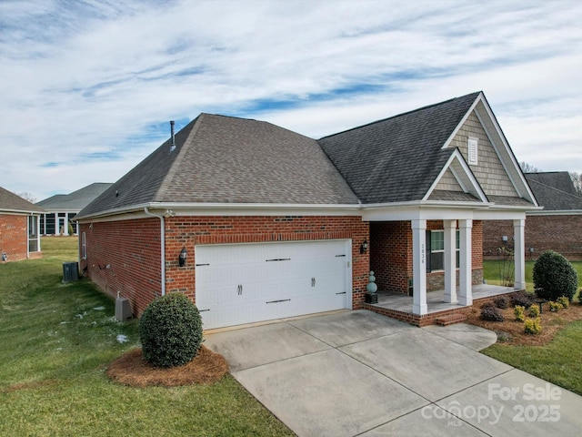 view of front of house with a garage, central AC, covered porch, and a front lawn