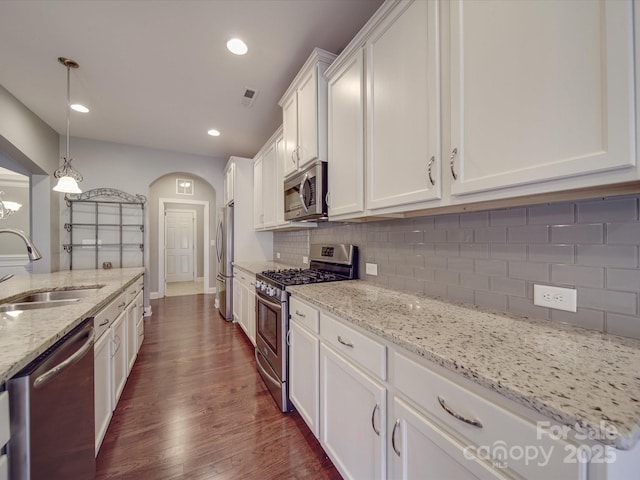 kitchen with sink, decorative light fixtures, appliances with stainless steel finishes, light stone countertops, and white cabinets