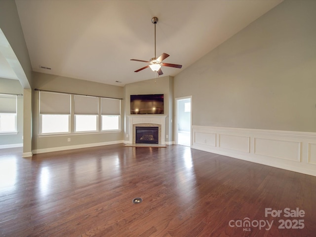 unfurnished living room with dark hardwood / wood-style flooring, a wealth of natural light, ceiling fan, and vaulted ceiling