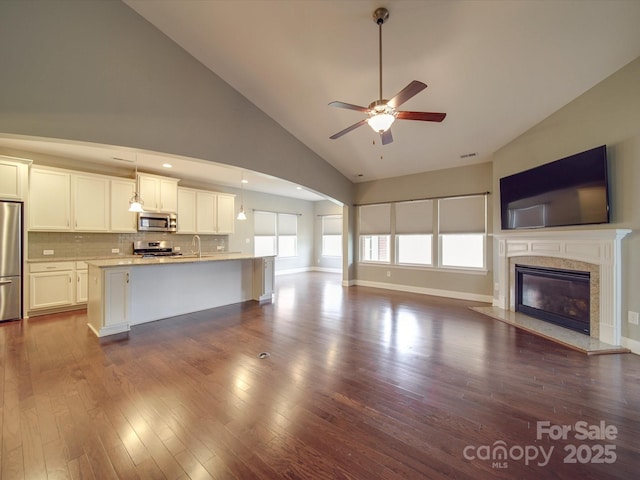 unfurnished living room with hardwood / wood-style floors, high vaulted ceiling, sink, ceiling fan, and a high end fireplace