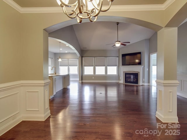 unfurnished living room featuring crown molding, lofted ceiling, ceiling fan with notable chandelier, and a tile fireplace