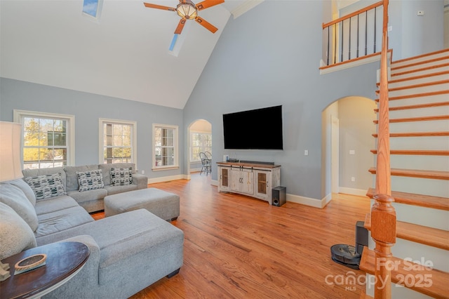 living room featuring ceiling fan, high vaulted ceiling, light wood-type flooring, and a wealth of natural light