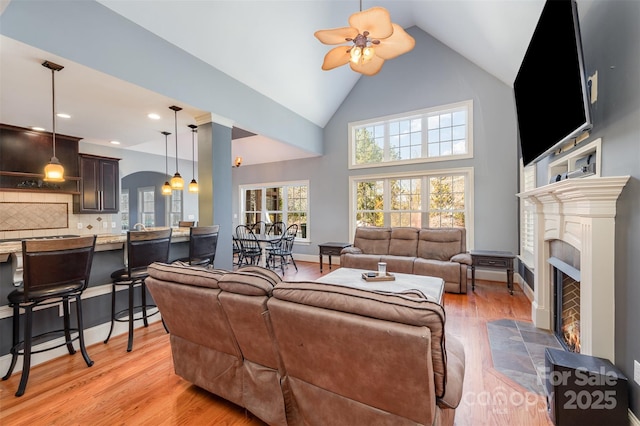 living room featuring light hardwood / wood-style flooring, high vaulted ceiling, and ceiling fan