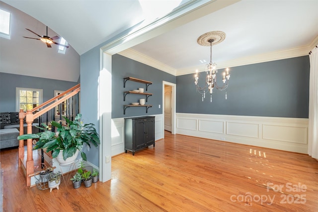 dining area featuring wood-type flooring, ornamental molding, and ceiling fan with notable chandelier