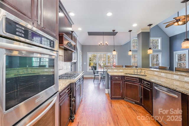 kitchen featuring vaulted ceiling, appliances with stainless steel finishes, decorative light fixtures, and sink