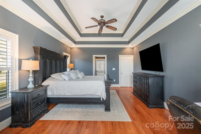 bedroom featuring hardwood / wood-style floors, a tray ceiling, ornamental molding, and ceiling fan