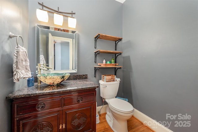 bathroom with hardwood / wood-style flooring, vanity, and toilet