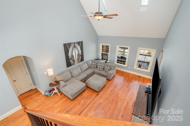 living room with ceiling fan, high vaulted ceiling, and light wood-type flooring