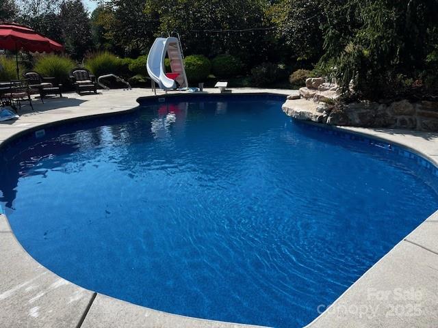 view of pool with a water slide and a patio area