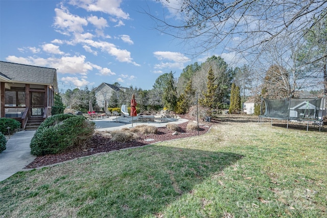 view of yard with a sunroom, a patio, and a trampoline