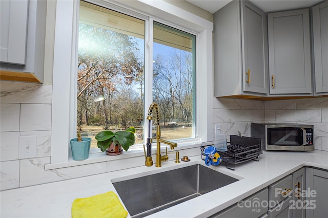 kitchen featuring tasteful backsplash, sink, and gray cabinetry