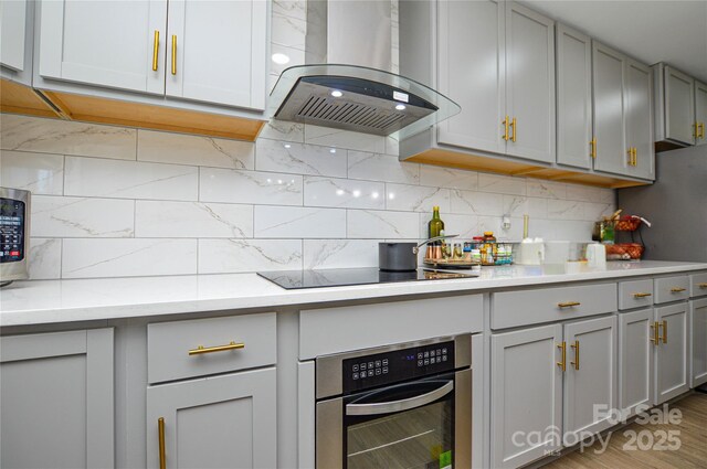 kitchen with gray cabinets, island exhaust hood, oven, and decorative backsplash