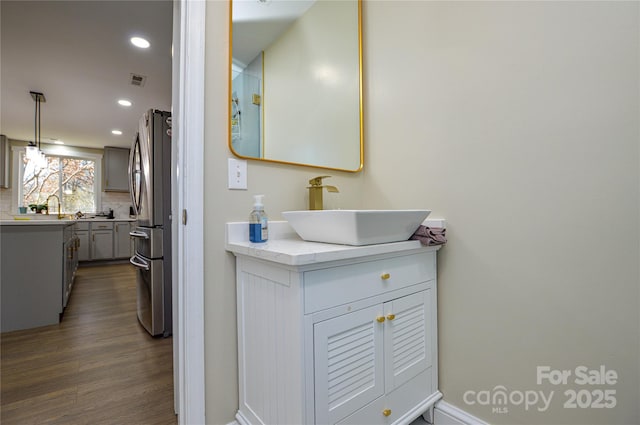 bathroom featuring vanity, hardwood / wood-style floors, and decorative backsplash