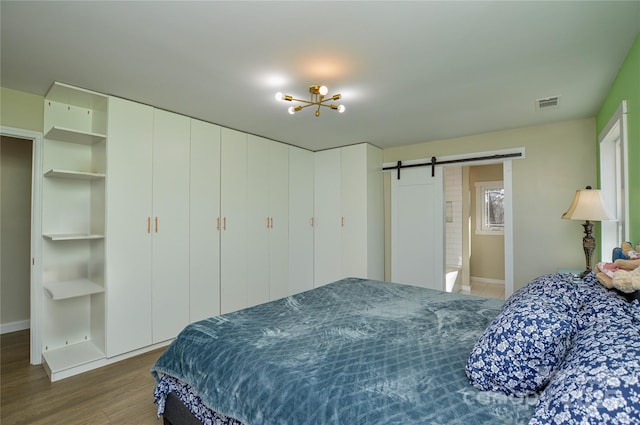 bedroom featuring a barn door and hardwood / wood-style floors