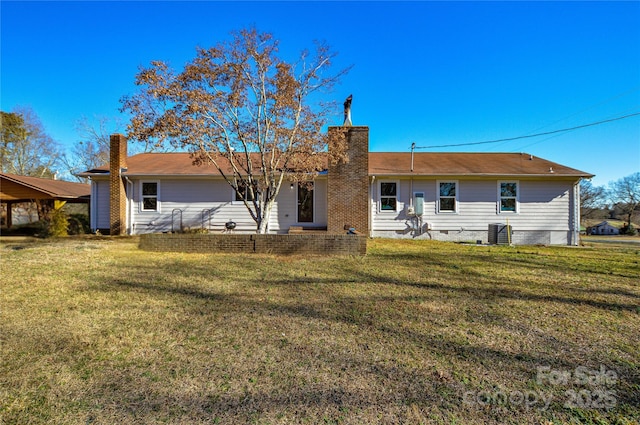 back of property with central AC and a lawn