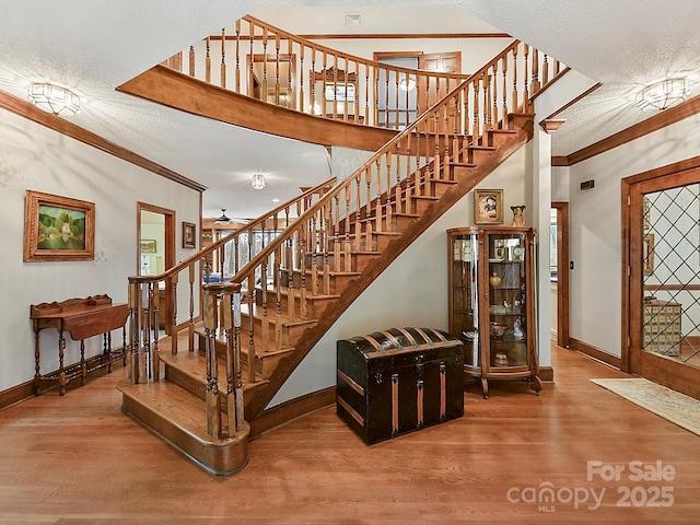 stairs featuring crown molding, hardwood / wood-style floors, and a textured ceiling