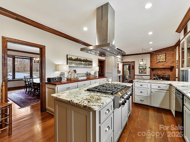 kitchen featuring island range hood, dark hardwood / wood-style flooring, stainless steel gas cooktop, crown molding, and light stone countertops