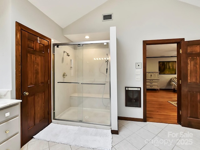 bathroom with lofted ceiling, heating unit, vanity, a shower with door, and tile patterned flooring