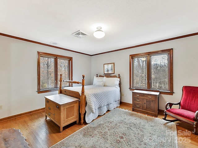 bedroom with ornamental molding and light hardwood / wood-style floors