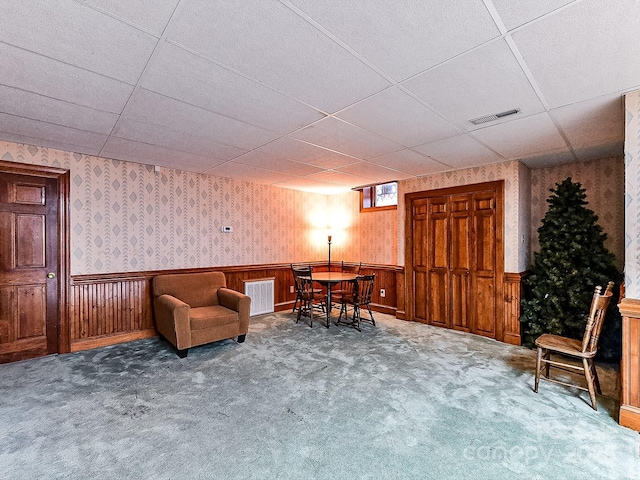 living area featuring a paneled ceiling and carpet