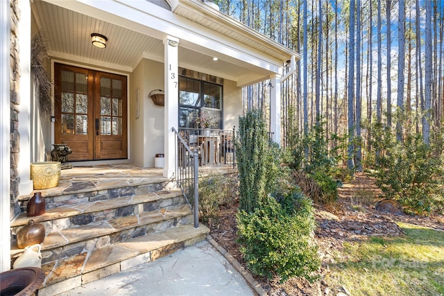 view of exterior entry with covered porch and french doors