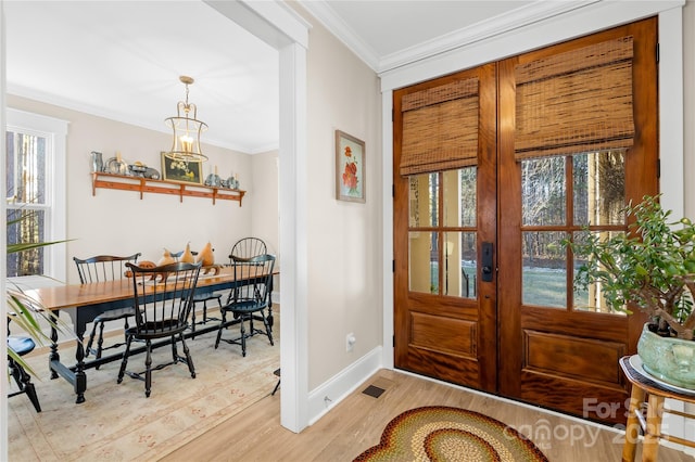 entrance foyer featuring light hardwood / wood-style flooring, crown molding, and french doors