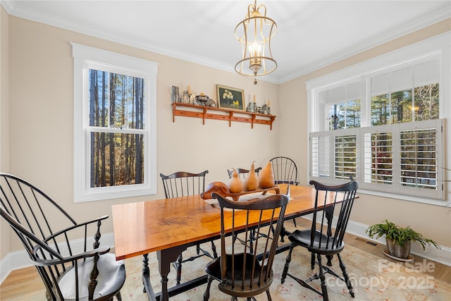 dining room with crown molding, light hardwood / wood-style floors, and a chandelier