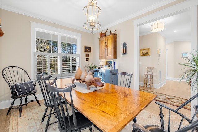 dining room with light hardwood / wood-style flooring, ornamental molding, and an inviting chandelier