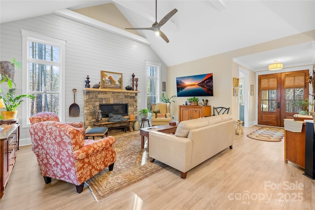 living room with light hardwood / wood-style floors, high vaulted ceiling, plenty of natural light, and a fireplace