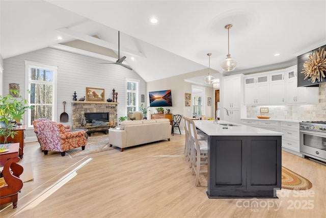 kitchen featuring pendant lighting, white cabinets, lofted ceiling, sink, and stainless steel stove