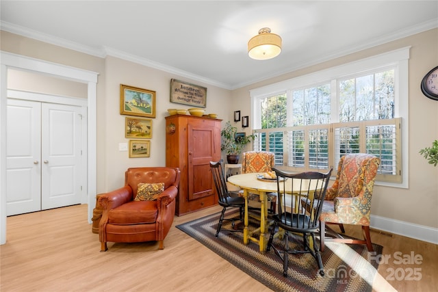 dining space featuring light wood-type flooring and crown molding