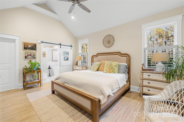 bedroom with light wood-type flooring, vaulted ceiling, ceiling fan, and a barn door