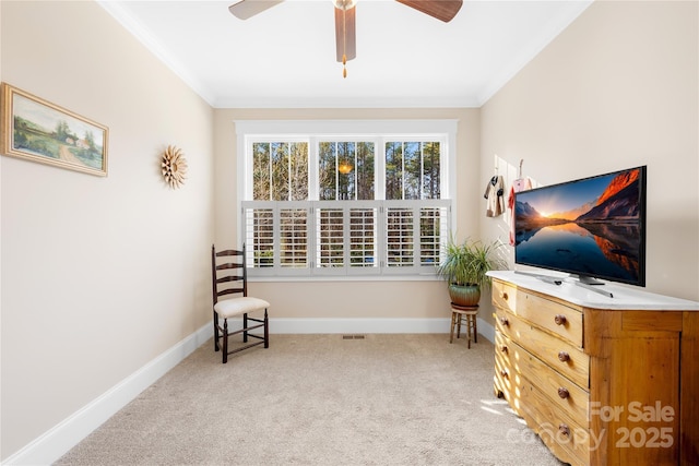 living area with ceiling fan, light carpet, and crown molding