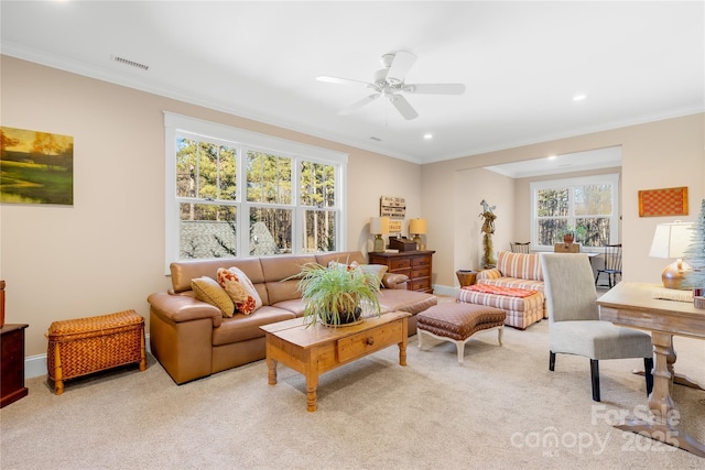 living room featuring ceiling fan, plenty of natural light, crown molding, and light carpet