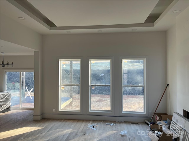 interior space featuring a tray ceiling and light hardwood / wood-style flooring