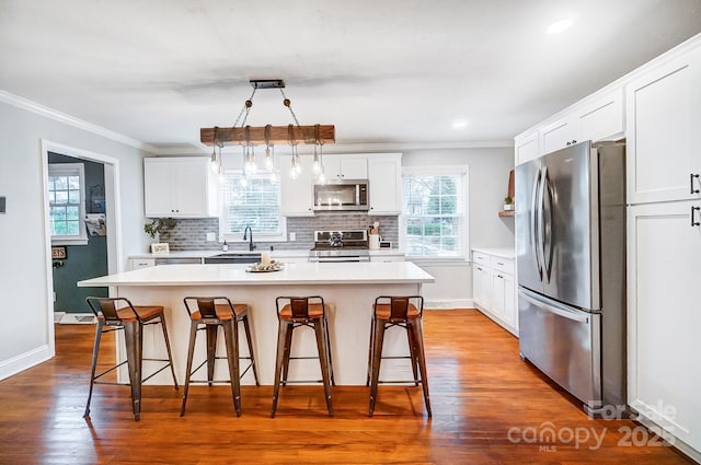 kitchen featuring pendant lighting, a breakfast bar area, white cabinets, a center island, and stainless steel appliances